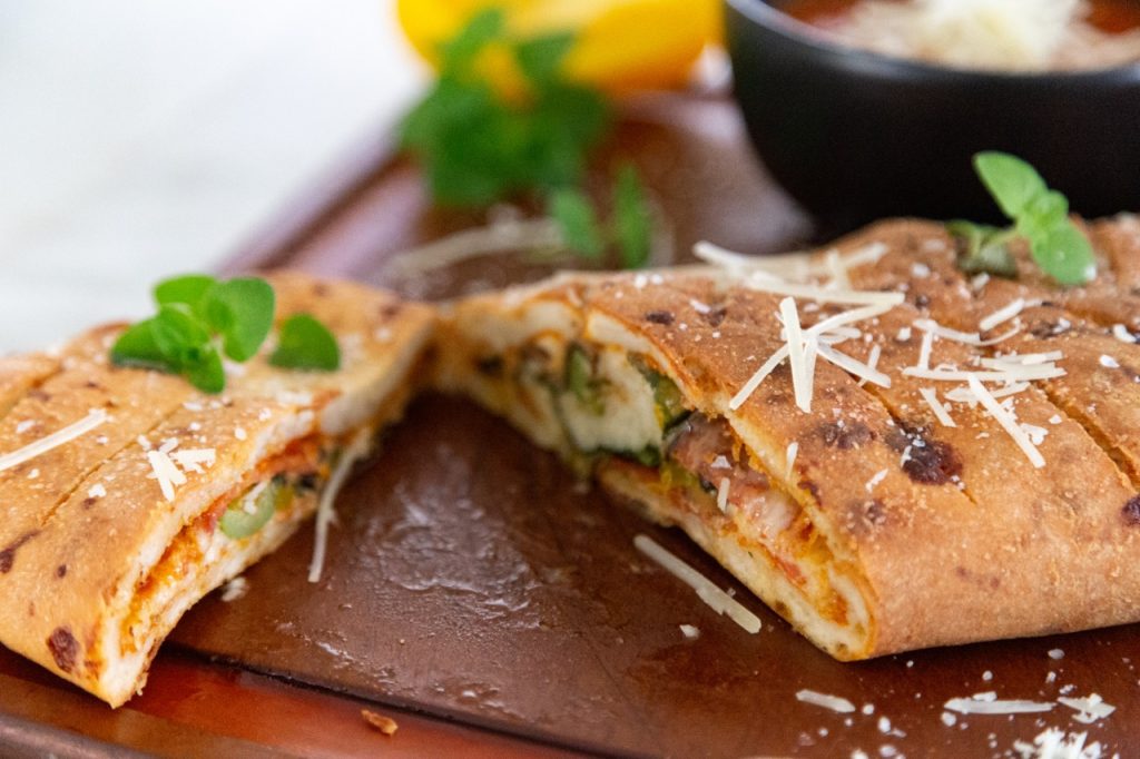 Ultimate Italian Stromboli - Gluten Free cut in half on a cutting board