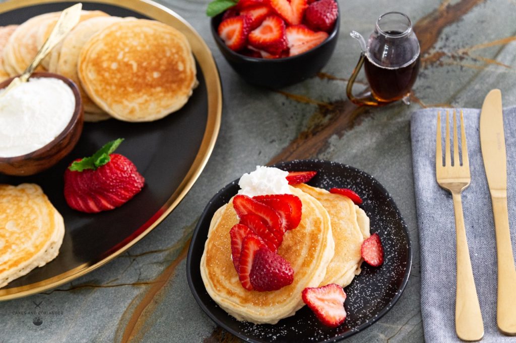 Gluten free griddle cakes with syrup, strawberries, and whipped cream