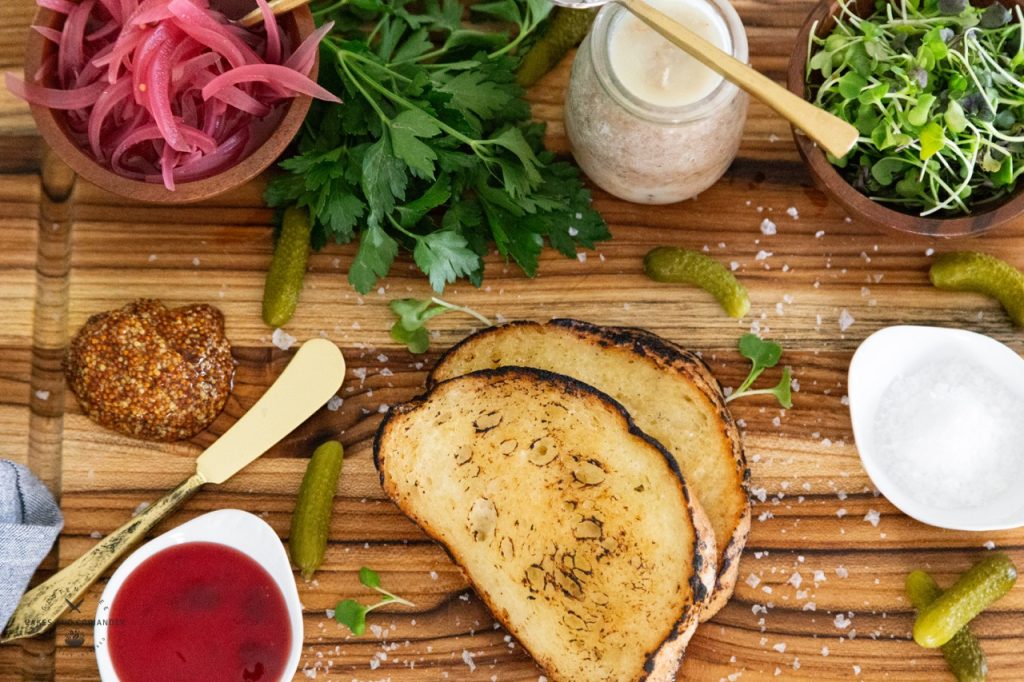 Overhead condiment platter for potted pork with pickled red onions, pickles, microgreens, whole grain mustard, and jam