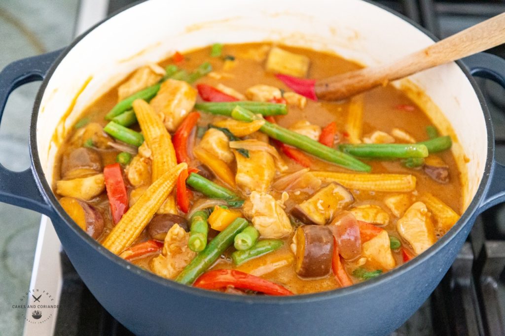 Peanut Butter Curry Recipe in a dutch oven with chicken, baby corn, eggplant, kaffir leaves, thai basil, green beans, and eggplant.