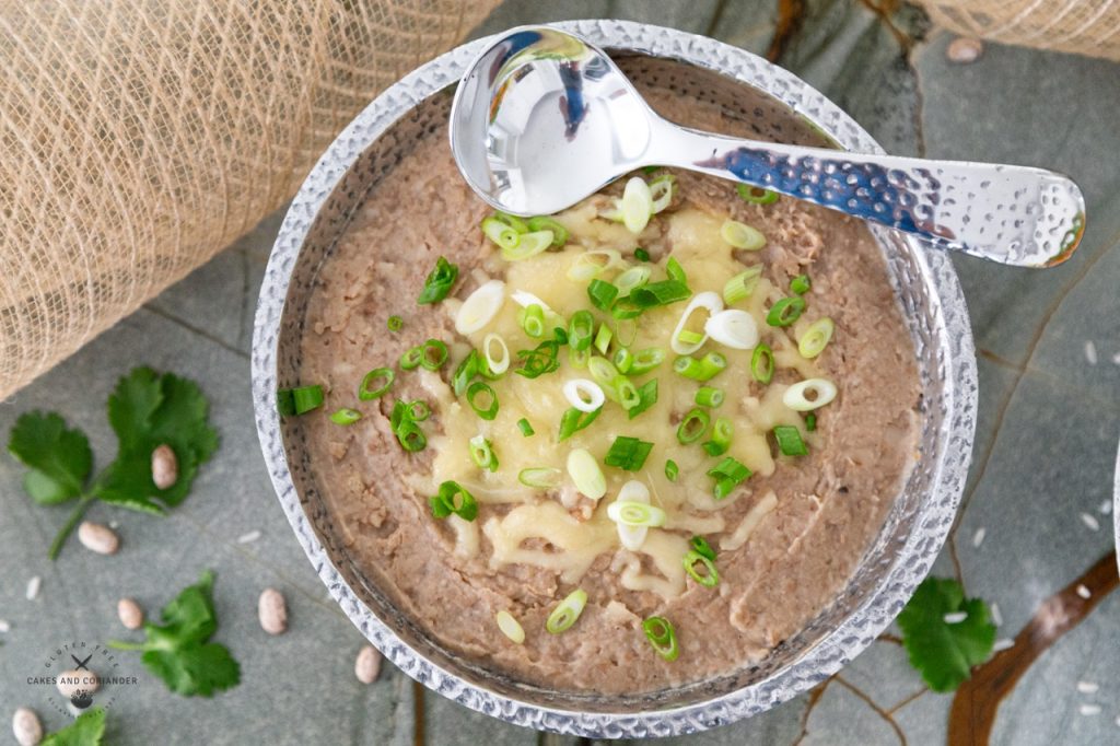 Authentic Refried beans in a pewter serving bowl with Chihuahua Cheese and Green Onions